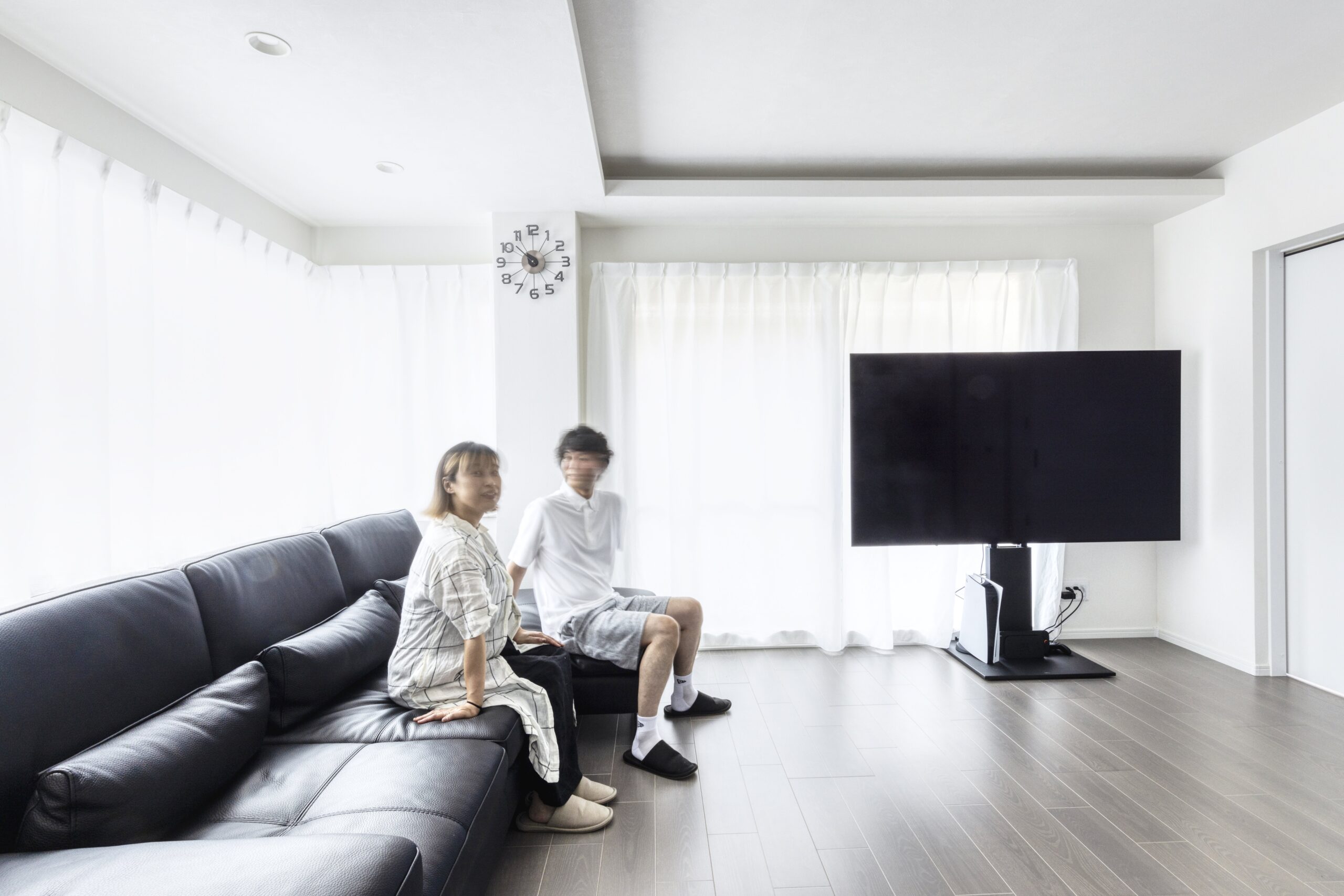リノベーションハイムの施工事例。黒のレザーソファとスタイリッシュなテレビスタンドを配置した、すっきり暮らせるリビング