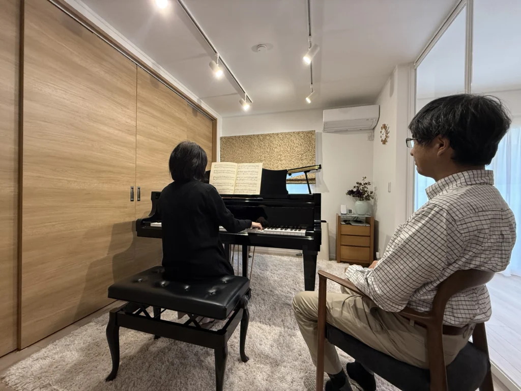リノベーションハイムの施工事例。防音や配置にこだわり、自宅で快適にグランドピアノの演奏を楽しむご家族の様子